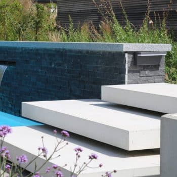 Origineel en luxueus tuinontwerp van zwembad met waterval en opvang niveauverschil door zwevende trappen in betonelementen