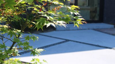 Eern japanse esdoorn als solitair naast een terras met onregelmatige vlakken in polybeton en basaltsplit.